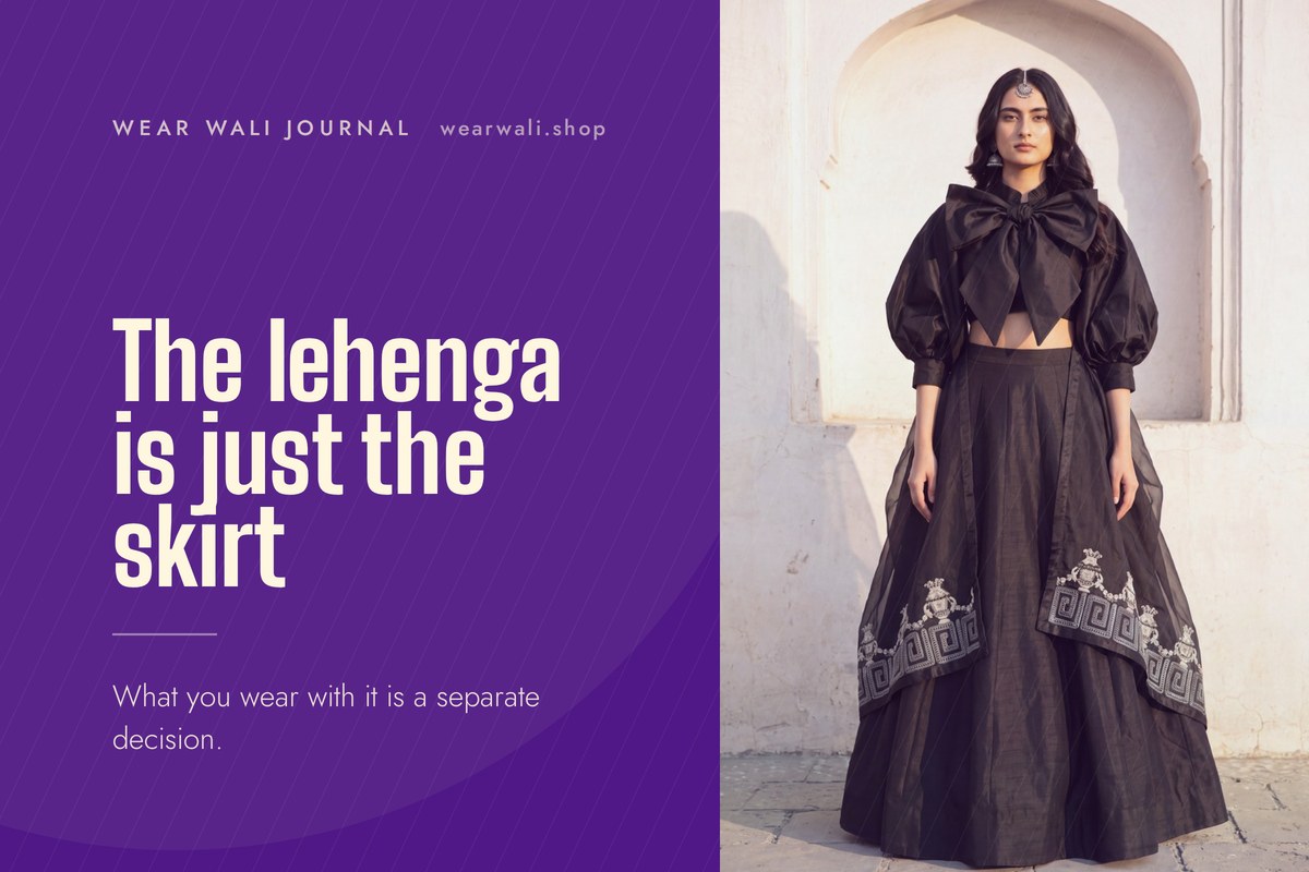 A black crop top worn with a separately cut full lehenga skirt, photographed against a pale arch.